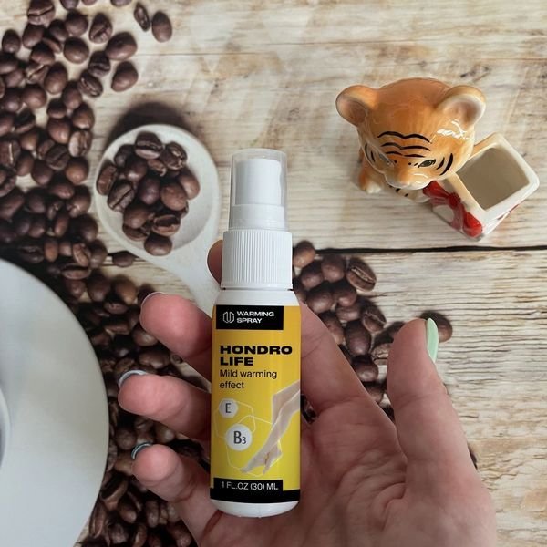 Flacone spray di Hondrolife da 30 ml tenuto in mano con chicchi di caffè sullo sfondo