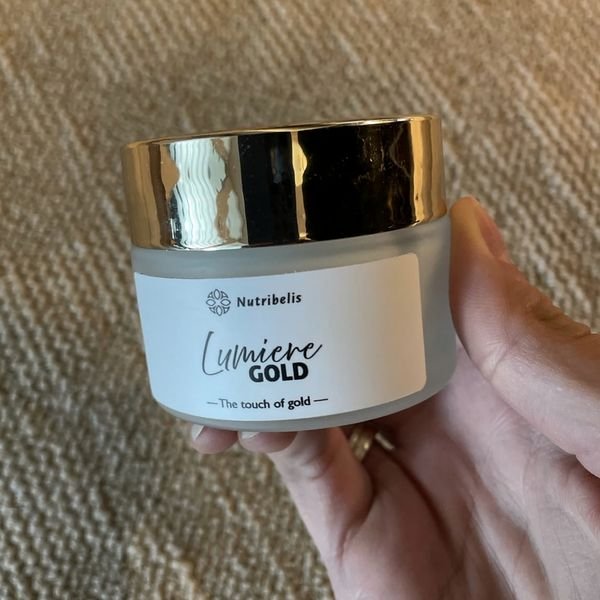 Vasetto di Lumiere Gold con tappo dorato tenuto in mano